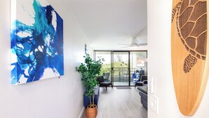 A modern living room with a large abstract painting, a potted plant, and a wooden wall decoration.