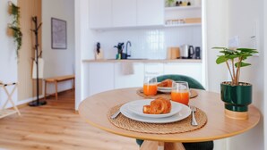 Una mesa de desayuno con croissants, zumo de naranja y una planta verde.