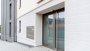 Un edificio moderno con puerta de entrada de vidrio, buzón metálico y pavimento de baldosas limpias.