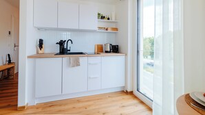 Una cocina moderna con armarios blancos, encimera de madera y ventana con vistas al exterior.