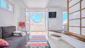 Un salon moderne avec un canapé, une table basse en verre, un tapis coloré et une vue sur l’extérieur.