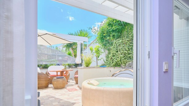 Un espace patio comprenant un jacuzzi, du mobilier d’extérieur et une pergola offrant de l’ombre.