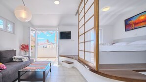 Une chambre d’hôtel moderne, équipée d’un canapé, d’une petite table, d’un banc, d’un lit et d’une grande fenêtre.
