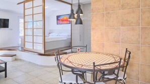 Une chambre d’hôtel moderne avec une table à manger ronde, un lit offrant une belle vue et un téléviseur fixé au mur.