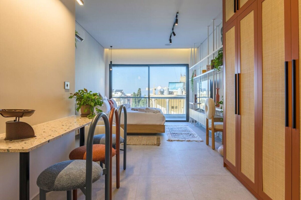 Un dormitorio moderno con una ventana grande, una cama, un escritorio y una silla.
