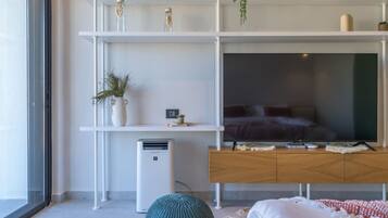Una sala moderna con un televisor de pantalla plana grande, armarios de madera y una estantería blanca con adornos.