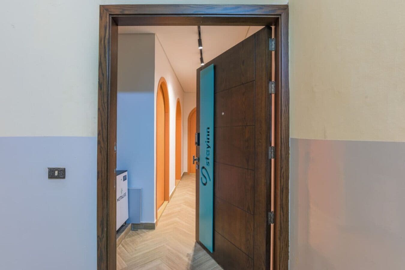 A hallway with a wooden door and a sign that reads "Stayinn".