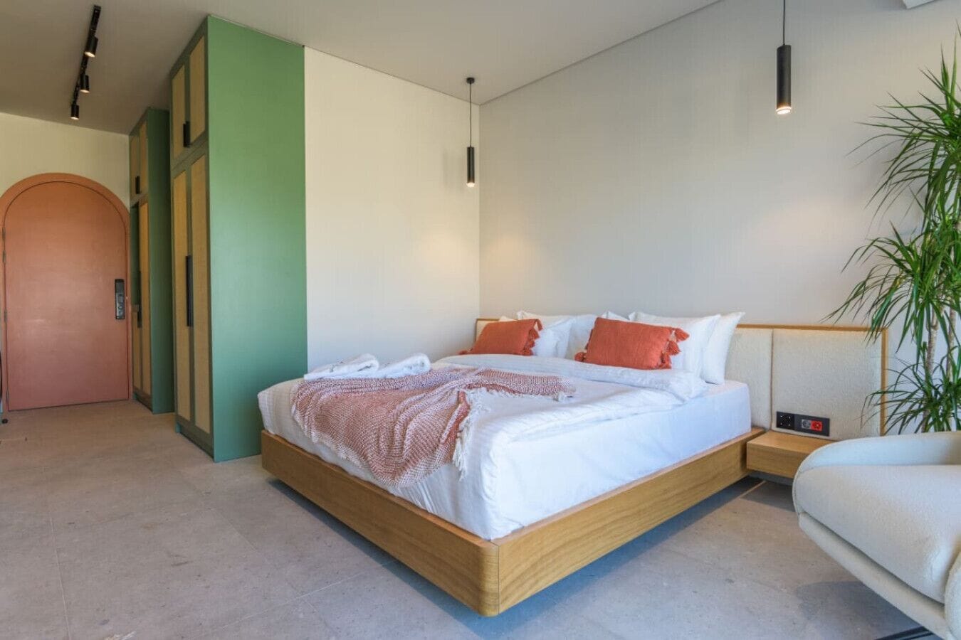 A modern bedroom with a wooden bed, white bedding, and a green accent wall.