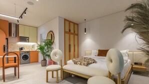 Un dormitorio moderno con una cama grande, dos sillones, una mesita y una mesilla de noche.