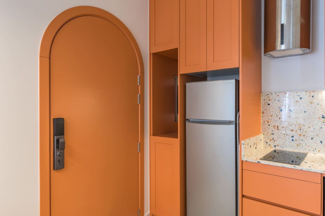 Eine Küche mit einem Edelstahlkühlschrank, Holzschränken und einer fleckigen Arbeitsplatte.