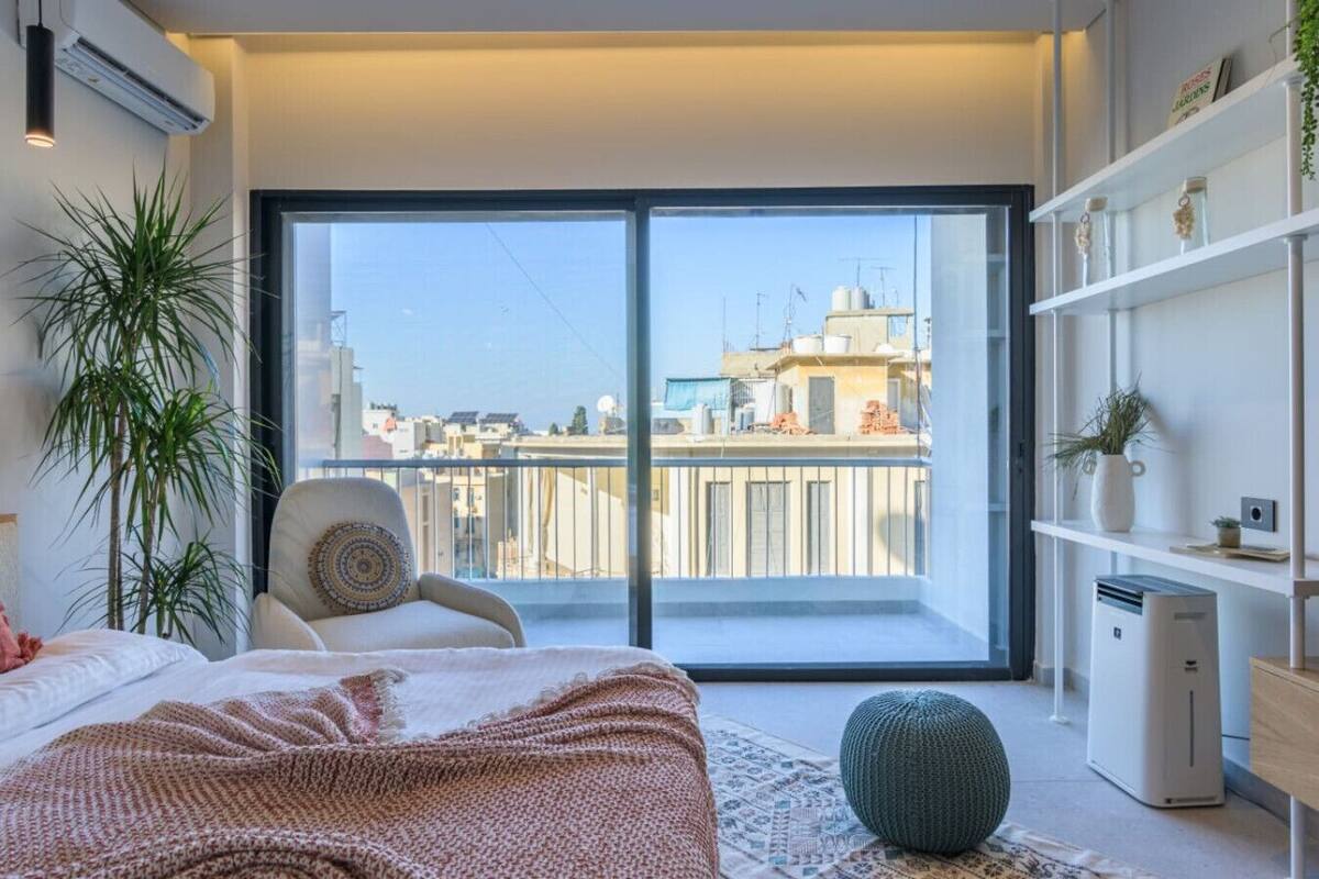 A modern bedroom with a large sliding glass door leading to a city view.
