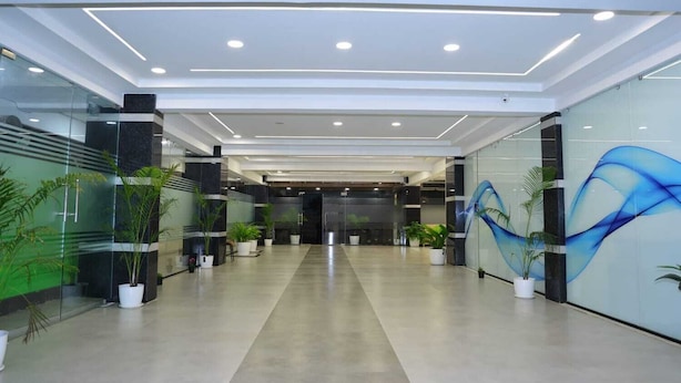 A modern lobby with glass walls, potted plants, and a blue abstract mural on the right wall. - Hotel Vista Airport Zone (Hyderabad)