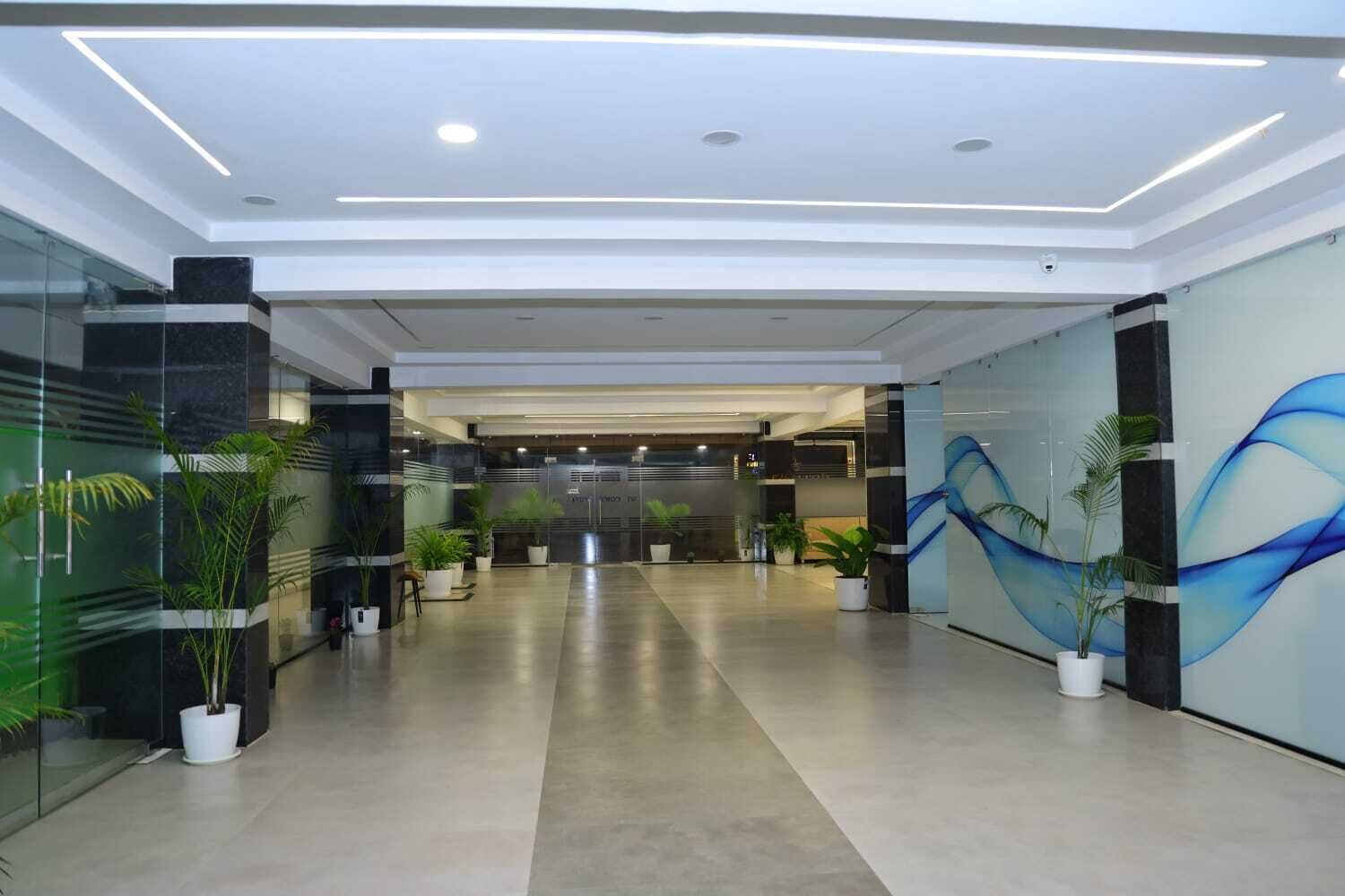 Un hall d’entrée moderne avec un mur en verre, des plantes en pot et une fresque murale bleue de style abstrait.