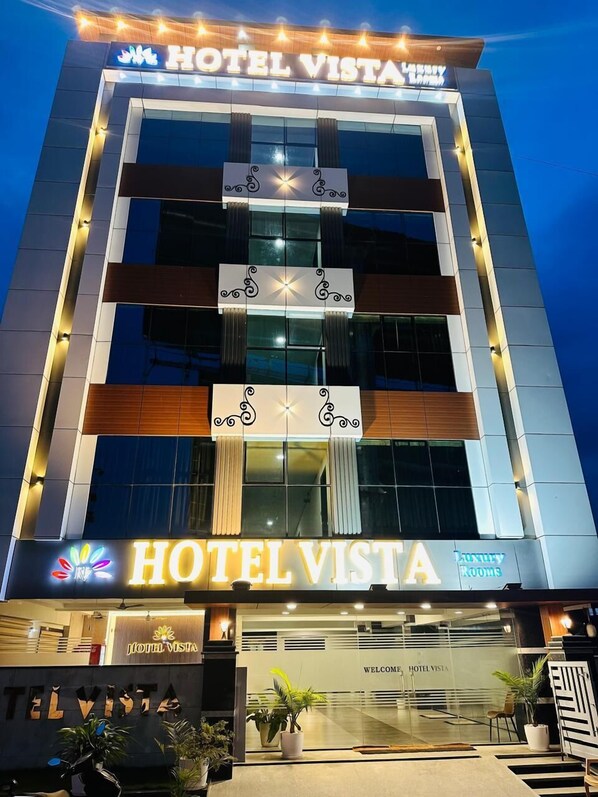 Un moderno edificio de hotel con un letrero destacado que dice "HOTEL VISTA" y "Habitaciones de Lujo" debajo.