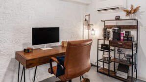 Ein moderner Arbeitsplatz mit einem Holztisch, einem Ledersessel, einem Flachbildschirm und einer Kaffeestation.