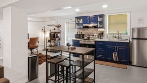 Eine moderne Küche mit blauen Schränken, Edelstahlgeräten und einem Essbereich mit Tisch und Stühlen.