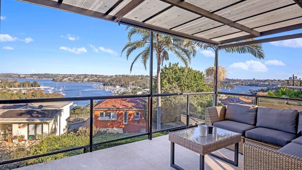 A balcony with a glass table and sofa, overlooking a marina and coastal town. - Metawise Luxe 6 Bed Ocean View Family Home in Seaforth (Sydney)
