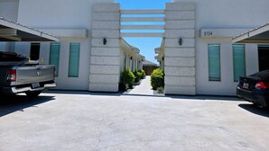 A parking area with a row of white buildings, each with a garage door and a number on the side. - Apartment With 3 Bedrooms 40 Minutes From South Padre (Weslaco)