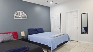 A bedroom with two beds, a nightstand, a wall-mounted tree decoration, and two white doors. - Apartment With 3 Bedrooms 40 Minutes From South Padre (Weslaco)