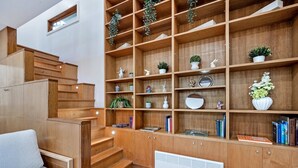 A modern interior with wooden shelving, books, decorative items, and a radiator. - Metawisebnb Stylish Loft Studio With Garden in Seaforth (Sydney)