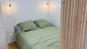 Et soveværelse med en seng, to hængende lamper og en træafskærmning.