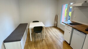 Et kompakt køkken med spiseplads, hvide skabe og en bænk.