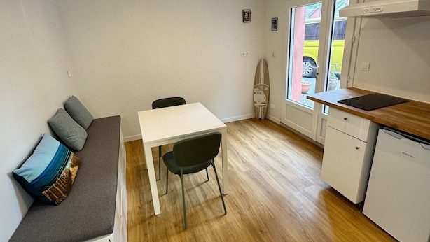 Et kompakt køkken med spiseplads, en indbygget bænk med hynder og udsigt gennem vinduet.