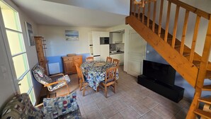 A dining area with a table and chairs, a sofa, a television, and a staircase.