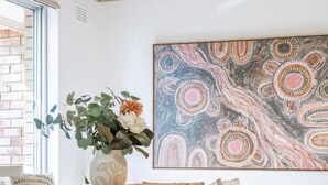 Un comedor con una mesa y sillas de madera, un jarrón con flores y un cuadro abstracto grande en la pared.