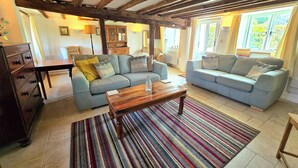 A cozy living room with two sofas, a wooden coffee table, and a striped rug.