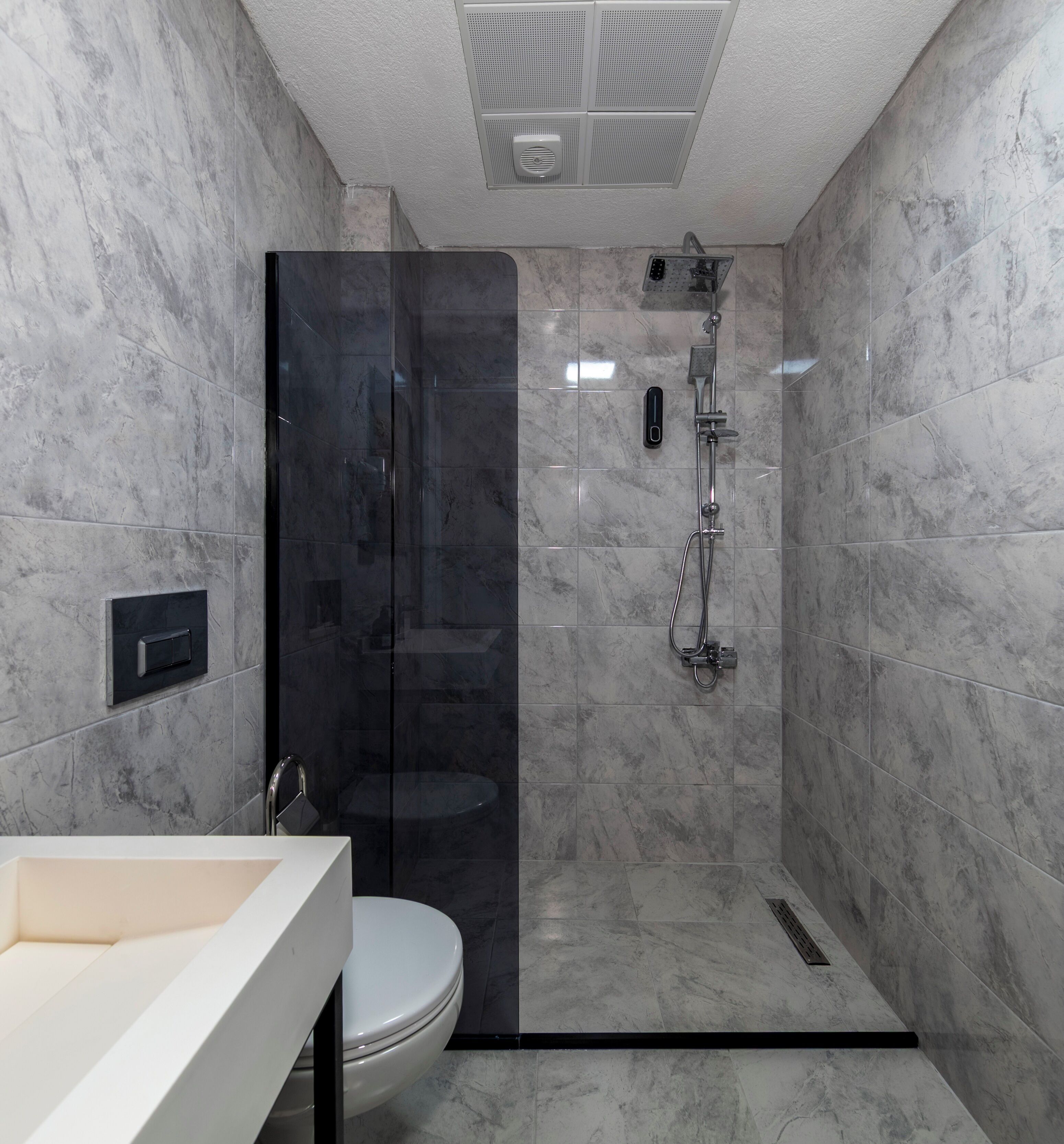 A modern bathroom with a glass-enclosed shower, a toilet, and a sink.