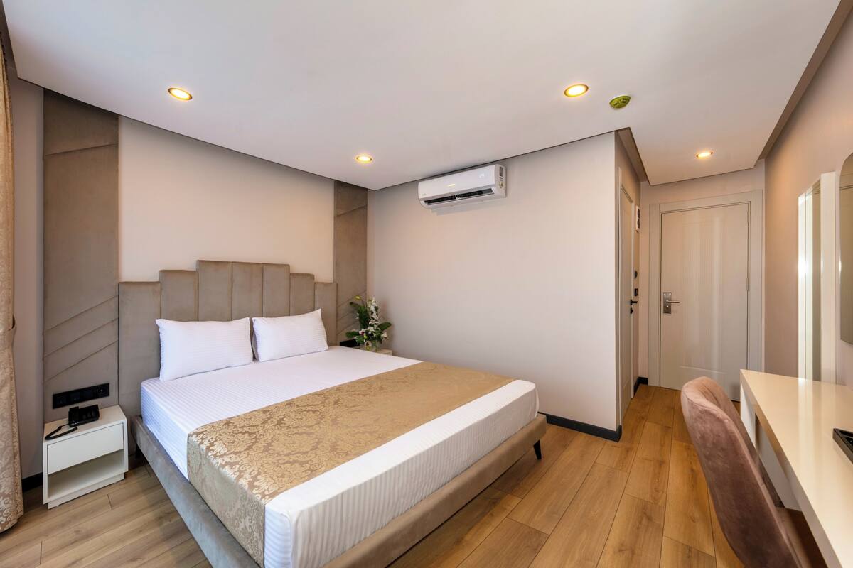 Ein modernes Hotelzimmer mit einem großen Bett, einem Nachttisch und einem Schreibtisch mit Stuhl.