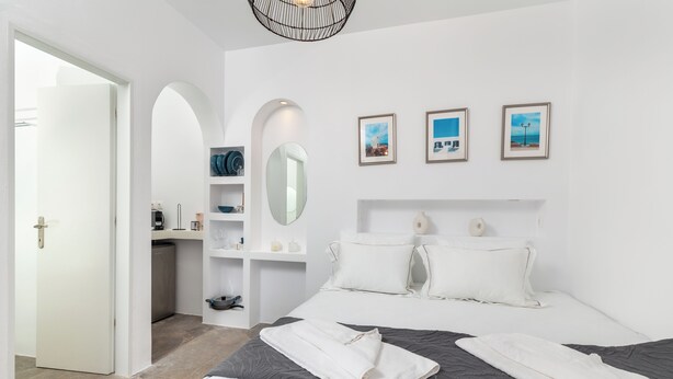 Een moderne slaapkamer met een groot bed, een inbouwkast, een spiegel en drie ingekaderde foto's aan de muur.