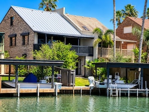 A waterfront property with a dock, a boat, and a house with a balcony overlooking the water.