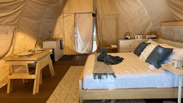 A cozy tent with a bed, bedside table, and a small desk with a chair. - Reef Resort Unit B8 (Island Garden City Of Samal)