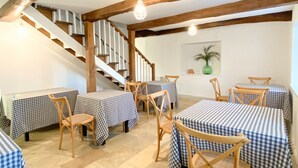 Un coin repas avec des nappes à carreaux, des chaises en bois et un escalier.