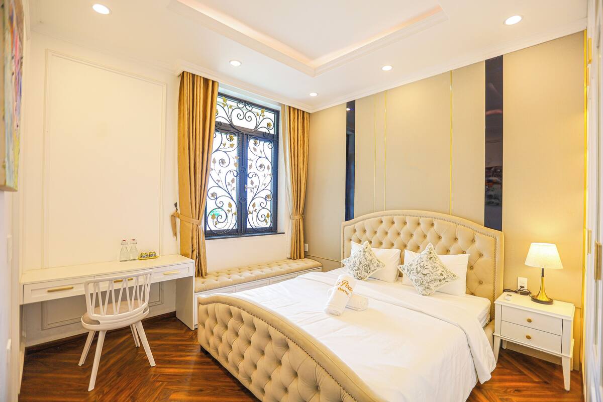 A bedroom with a large bed, a desk, and a chair.