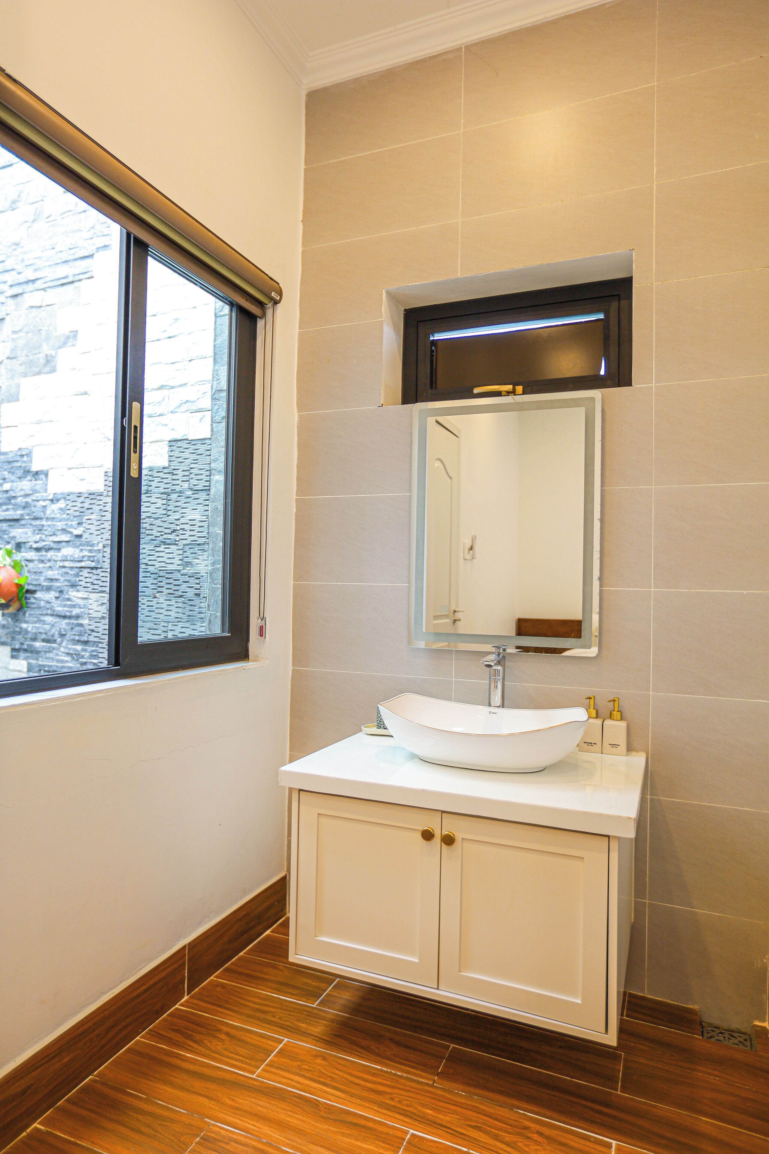 A bathroom with a white sink, a mirror, and a window with blinds.