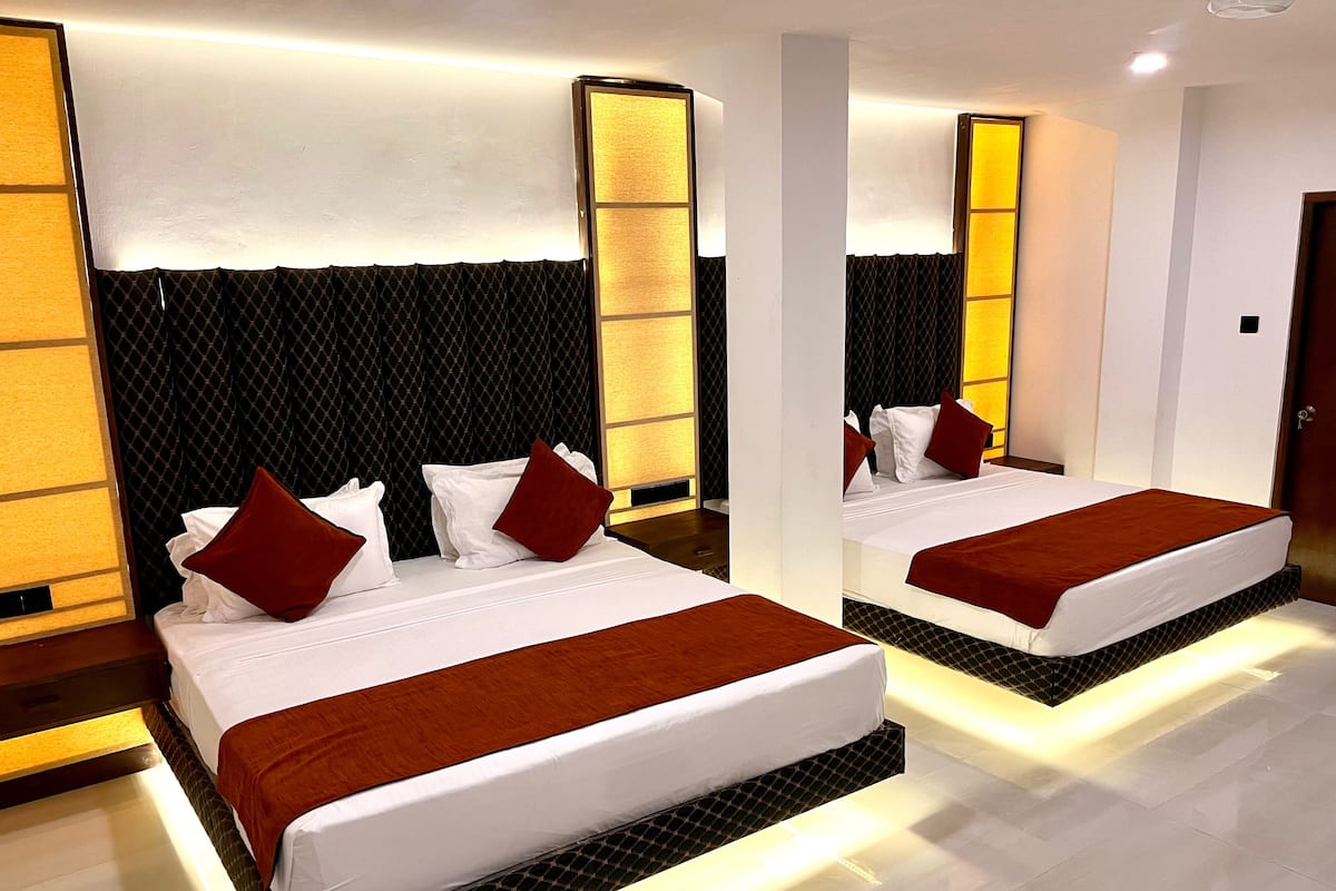 A modern hotel room with two beds, a large mirror, and a unique black and white patterned headboard.
