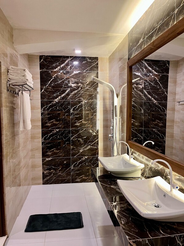 A modern bathroom with a large mirror, two sinks, and a towel rack.
