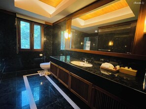 A modern bathroom with a large mirror, dark marble flooring, and a window with a view of trees. - Kiri Anda Villa Phuket (Rawai)