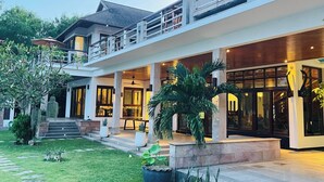 Une villa moderne dotée d’un vaste patio extérieur, d’une terrasse supérieure couverte et d’un jardin bien entretenu.