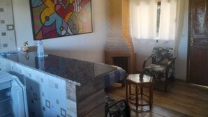 Une cuisine dotée d’un plan de travail en granit, d’un four à pizza et d’un coin repas avec une chaise et une table.
