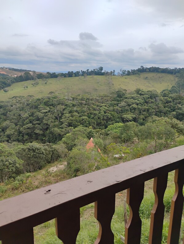 Blick vom Balkon auf eine üppige, grüne Landschaft mit einem Hügel im Hintergrund.