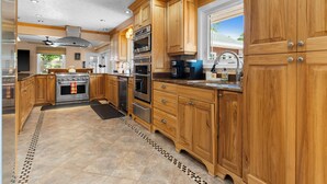 Een moderne keuken met houten kastjes, roestvrijstalen apparatuur en een betegelde vloer.