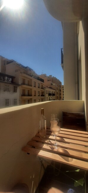Ein Balkon mit Tisch, einer Flasche und einem Glas.