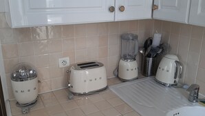 Una cuina amb electrodomèstics blancs, com un tostadora, amassadora i bullidor.