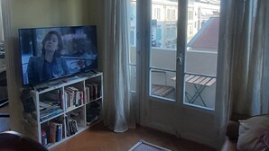 Un saló amb televisió, prestatges plens de llibres, una cadira vermella, una taula petita i un sofà.