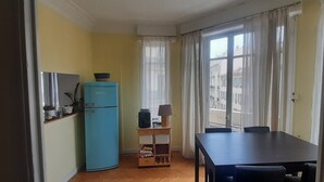Una cuina compacta amb un frigorífic blau, un petit armari de fusta i una taula de dinar amb cadires.