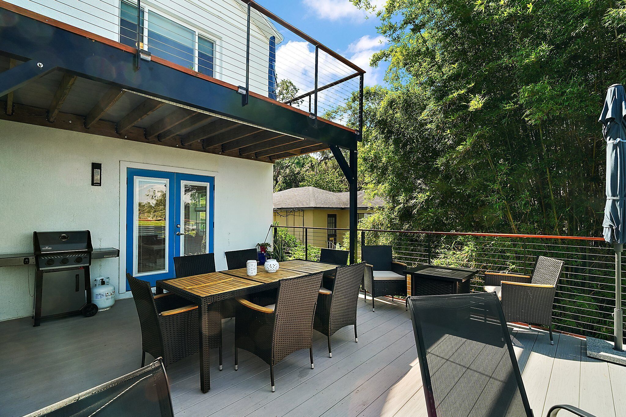 An outdoor patio with a dining table, chairs, and a grill.